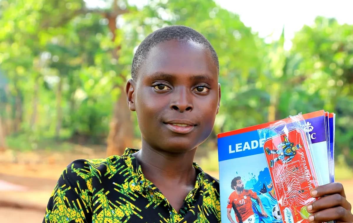 Philip holding notebooks with a shy smile